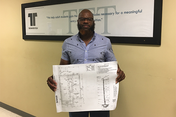 Tony Jones holds up blueprints for house he plans to build.